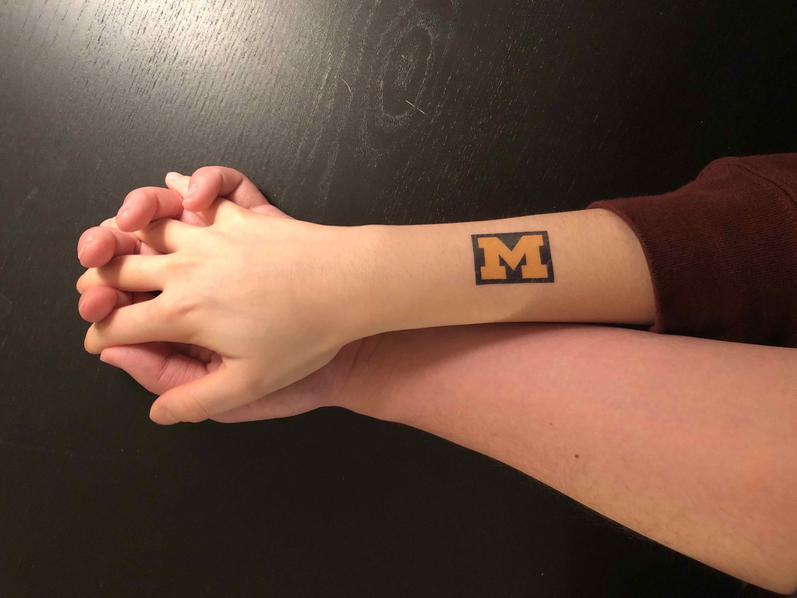 hands clasped with Michigan tattoo